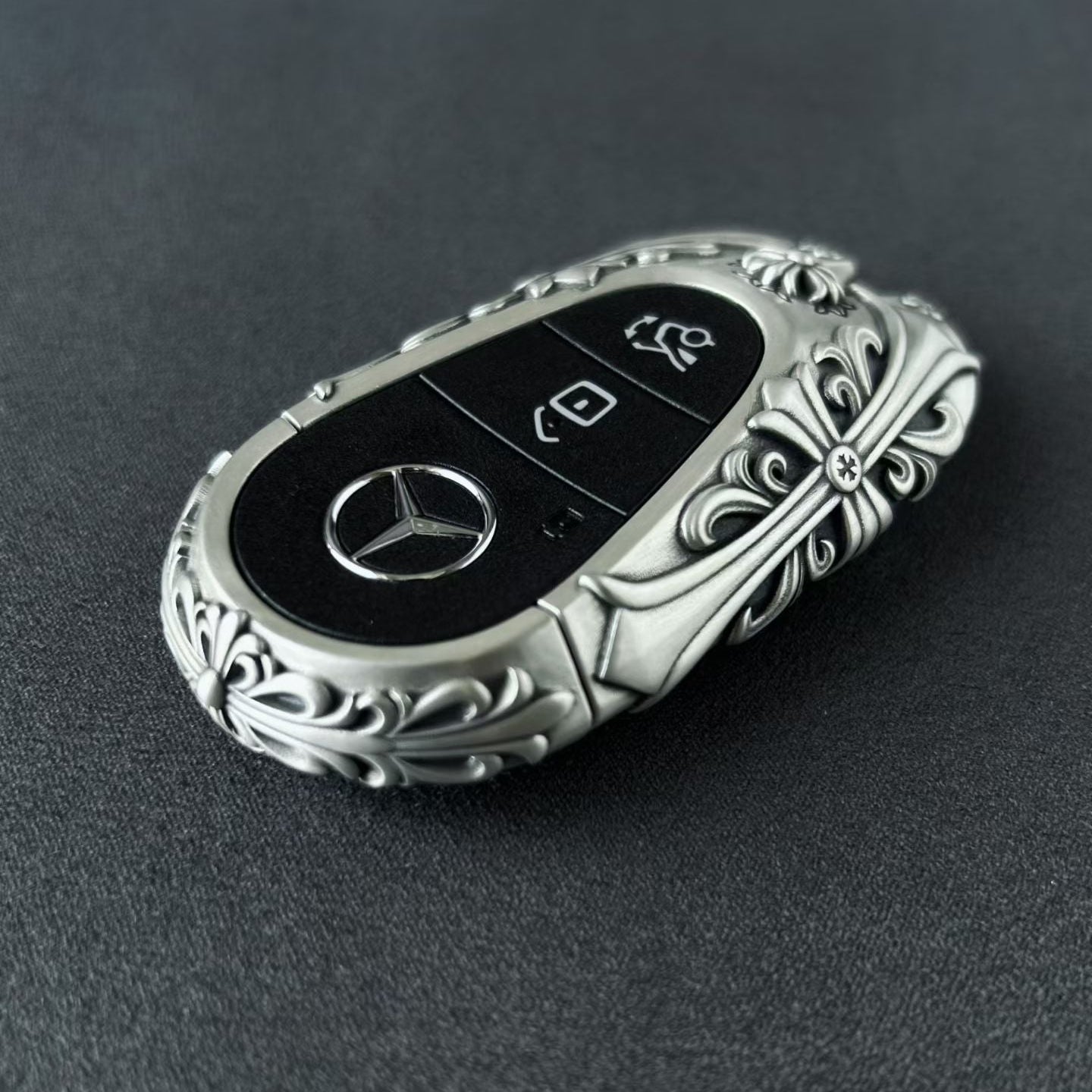 Close detail of the back engraving texture on a Mercedes-Benz key case, showing depth, surface control, and material character