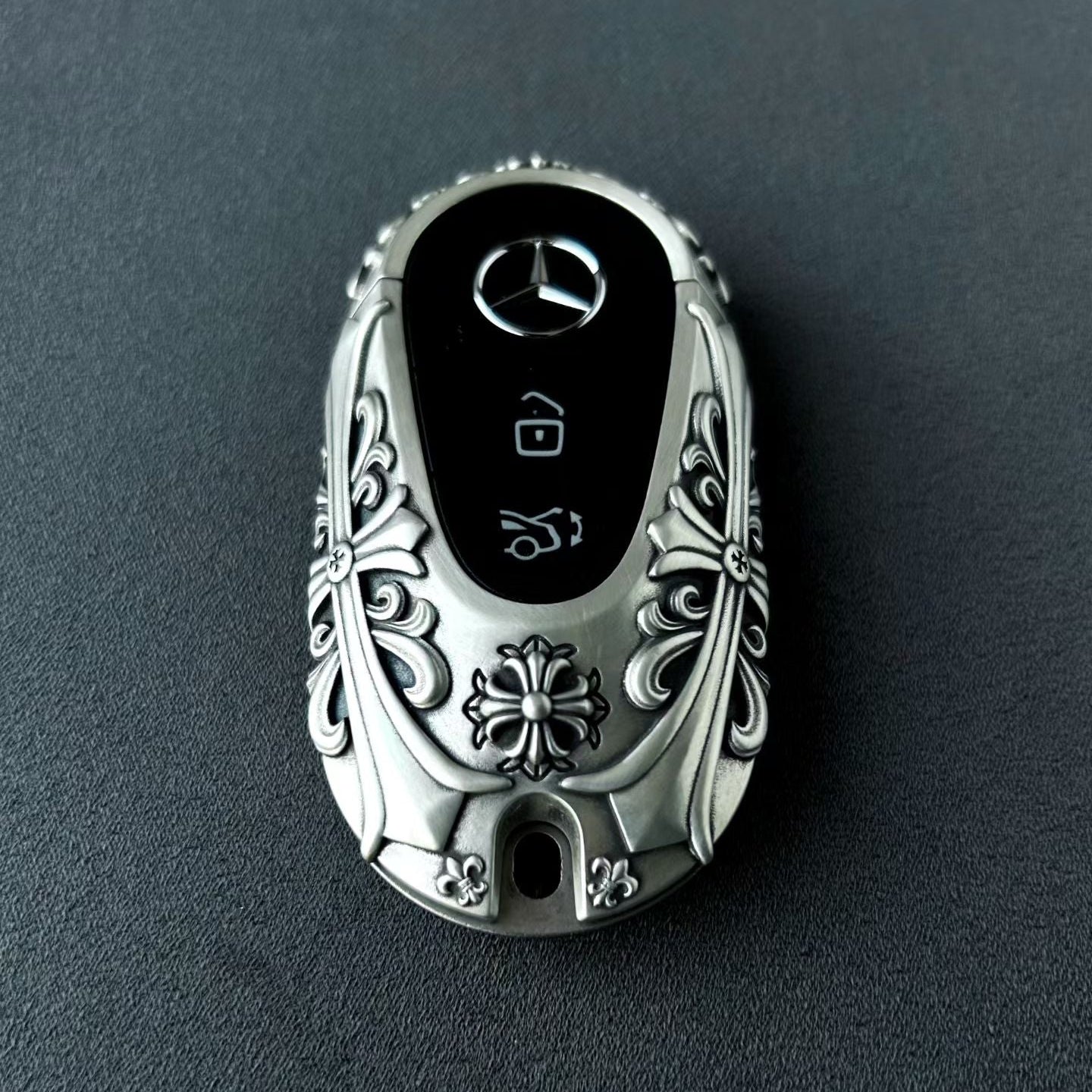 Mercedes rounded capsule key case diagonal rear angle showcasing uniform relief pattern and weighty precision from multiple perspectives